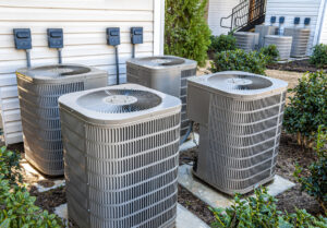 Horizontal shot of four apartment air conditioners outside.